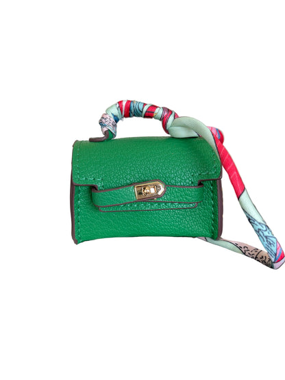 A miniature green pebbled leather handbag with a colorful patterned silk strap and gold-tone hardware.